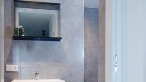 A modern bathroom with a large mirror, dark cabinetry, and a wicker basket on the floor. - Rural B&B with a beautiful outdoor view and a village atmosphere! (Rhenen)