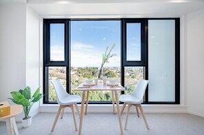 A modern dining area with a table set for two, large windows, and a potted plant.