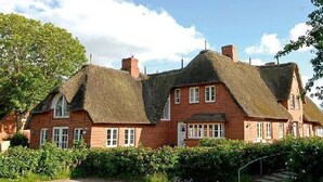 A traditional red brick house with thatched roofs and white-framed windows. - Ferienwohnung in Wrixum, mit 3- Zimmern auf 60m² im Reetdachhaus (Wrixum)