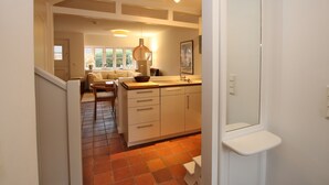A kitchen with a white countertop, a hanging light fixture, and a window with a view of the outdoors. - Ferienwohnung in Wrixum, mit 3- Zimmern auf 60m² im Reetdachhaus (Wrixum)