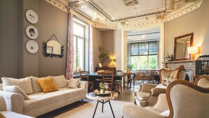 Amplia sala de estar con un sofá, sillones y un comedor con mesa y sillas.
