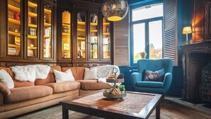 Una sala de estar acogedora con un sofá modular, una mesa de centro con un adorno decorativo, un sillón azul y una chimenea.
