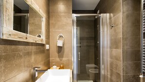 Ein modernes Badezimmer mit einem großen Waschbecken, einem Spiegel und einer Duschkabine.
