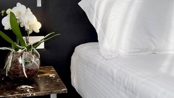 A modern bathroom with a white bathtub, a showerhead, and a small table with a vase of white orchids.