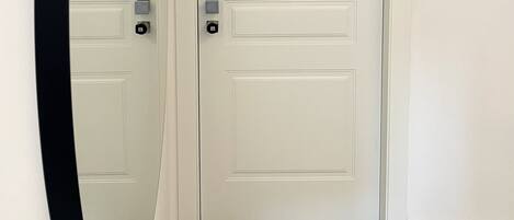 A white door with the number 103, a black-framed mirror, and a carpeted floor.