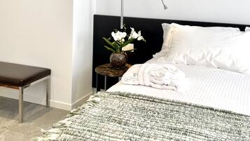 A bedroom with a bed, bedside table, bench, and a wall with three books.