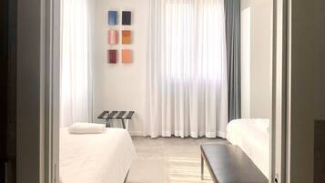 Habitació d'hotel amb un llit, una banca, un escriptori i una paret amb quadres.
