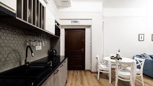 Een moderne keuken met een zwart aanrecht, een mozaïekachtergrond en een houten deur.