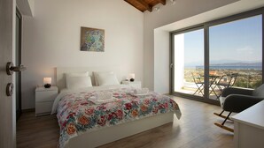 Une chambre avec un grand lit, une table de chevet, une chaise et une vue sur l’extérieur.