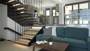 Un salon moderne comprenant un escalier, un canapé, une table basse et un coin repas avec des chaises et une table.
