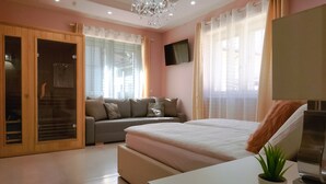 A bedroom with a bed, a sofa, a TV, and a wooden wardrobe. - Klemi (Trento)