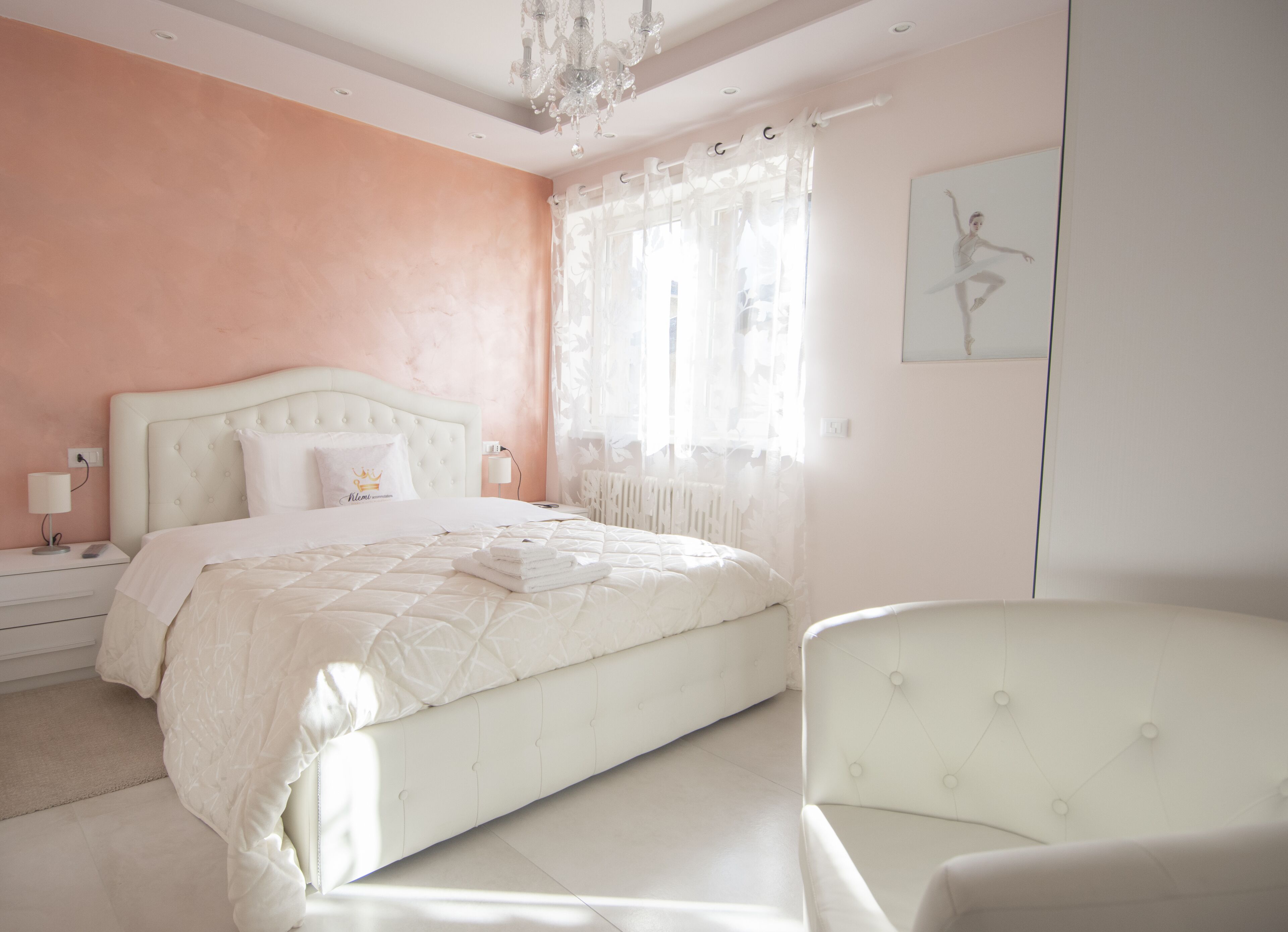 Une chambre à coucher avec un grand lit, une table de chevet, une chaise et un lustre.