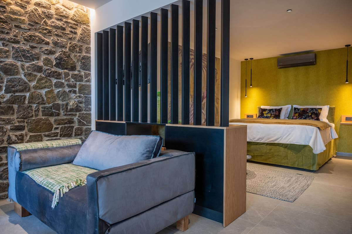 A modern bedroom with a stone wall, a sofa, a bed, and a decorative panel.