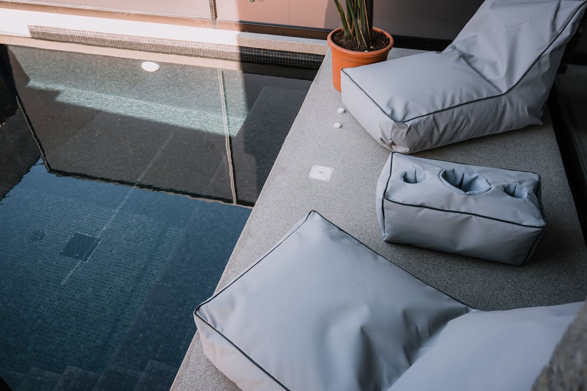 A modern outdoor seating area with grey cushions and a potted plant.