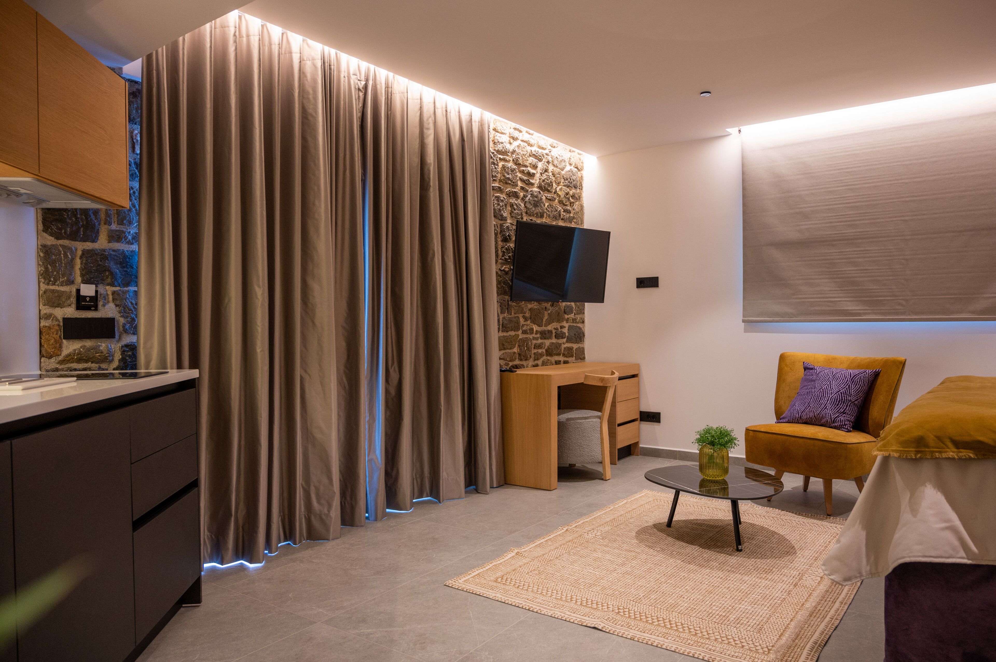 Una sala de estar moderna con una pared de acento de piedra, un televisor de pantalla plana, un sillón cómodo y una pequeña mesa de centro.