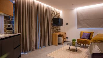 Una sala de estar moderna con una pared de acento de piedra, un televisor de pantalla plana, un sillón cómodo y una pequeña mesa de centro.