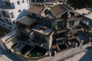 Una casa moderna de varios pisos con fachada de piedra, varios balcones y una piscina.