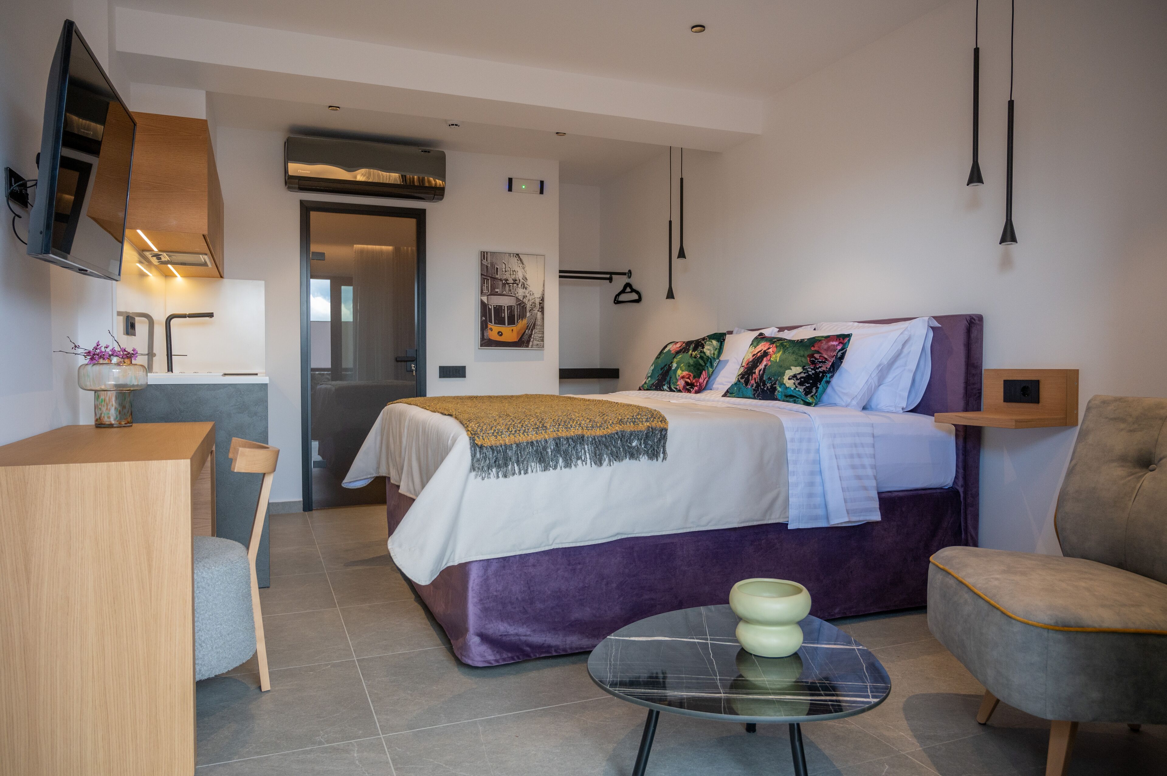 Een moderne hotelkamer met een bed, een bureau, een stoel, een televisie en een badkamer.
