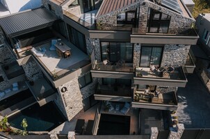 Una casa de varios pisos con fachada de piedra, zonas de estar al aire libre y una piscina.