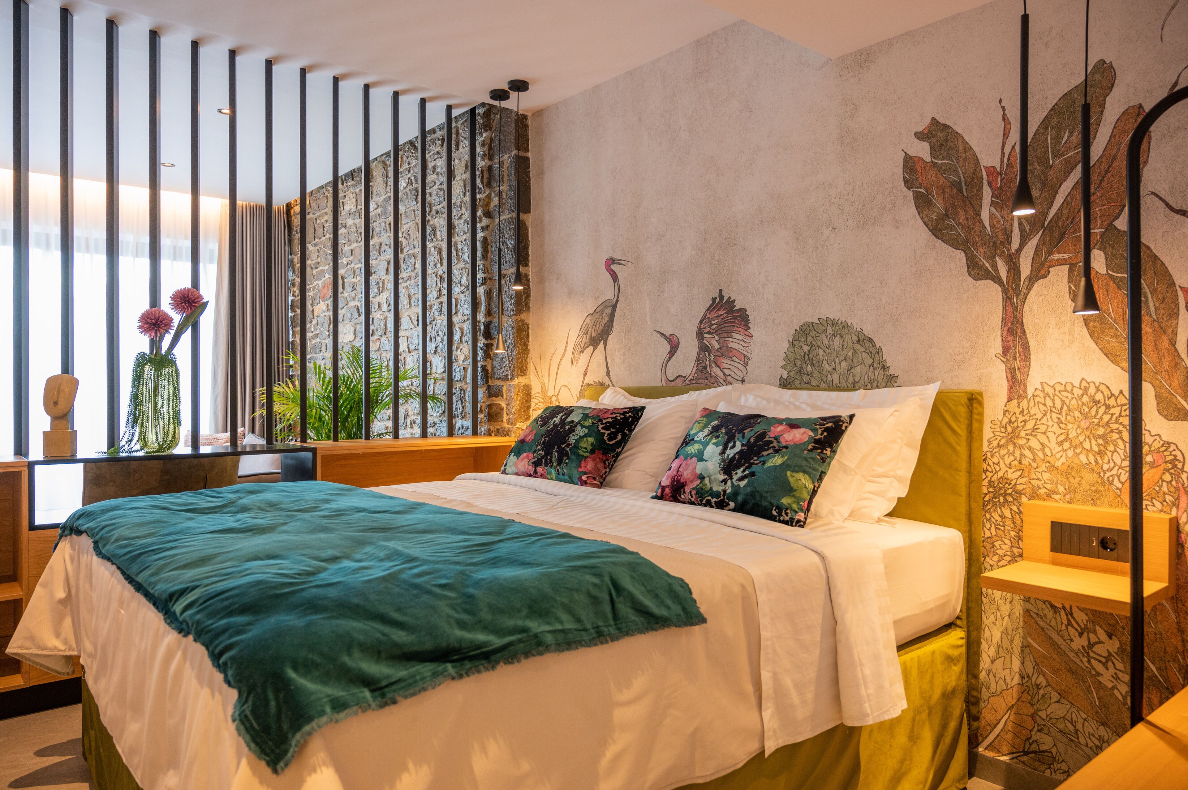 Un dormitorio moderno con una cama grande, una pared de piedra y un mural de pájaros.