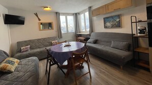 A cozy living room with a round table, sofas, a TV, and a painting on the wall.