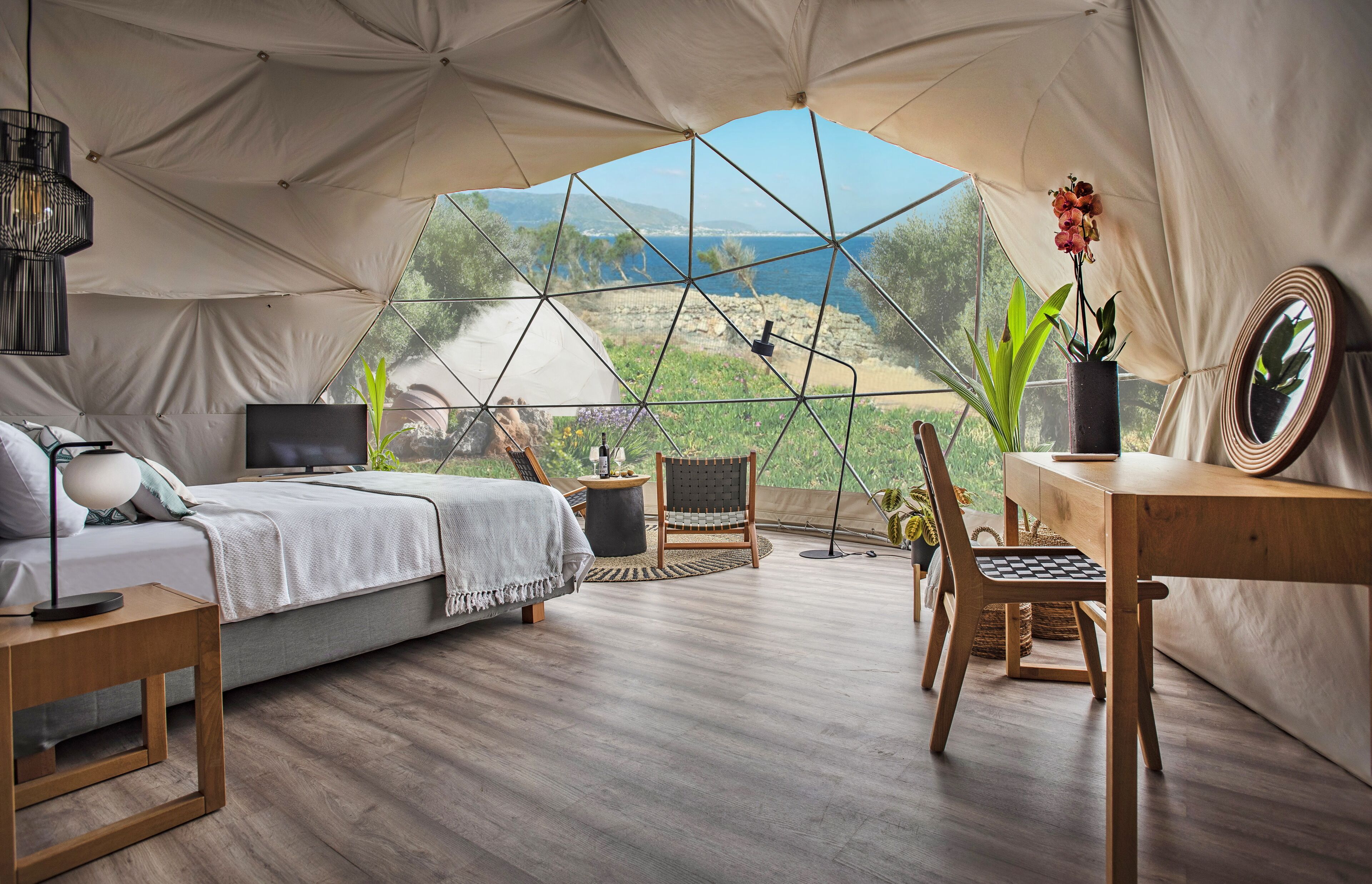Alojamento tipo tenda com cama, área de estar e vista para o mar.