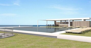 Un área de piscina moderna al aire libre con una zona de estar cubierta y sillones de descanso.