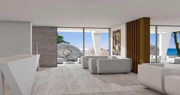 Un interior moderno con ventanas amplias, muebles blancos y vista al mar.