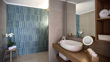 A modern bathroom with a large white sink, wooden vanity, and a blue-tiled shower area.