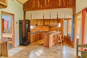 Enjoy cooking in this kitchen with a refrigerator, sink, and wooden island with stools.