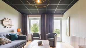 A modern living room with a grey sofa, two armchairs, a wooden coffee table, and a unique circular light fixture. - Charming historical house, pets allowed, private parking (Vicq-sur-Mer)