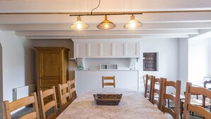 A dining area with a marble table, wooden chairs, white cabinets, and pendant lighting. - Charming historical house, pets allowed, private parking (Vicq-sur-Mer)