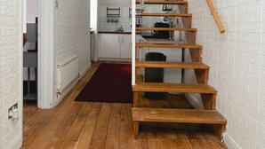 A wooden staircase with a red carpet leading to a kitchen area.