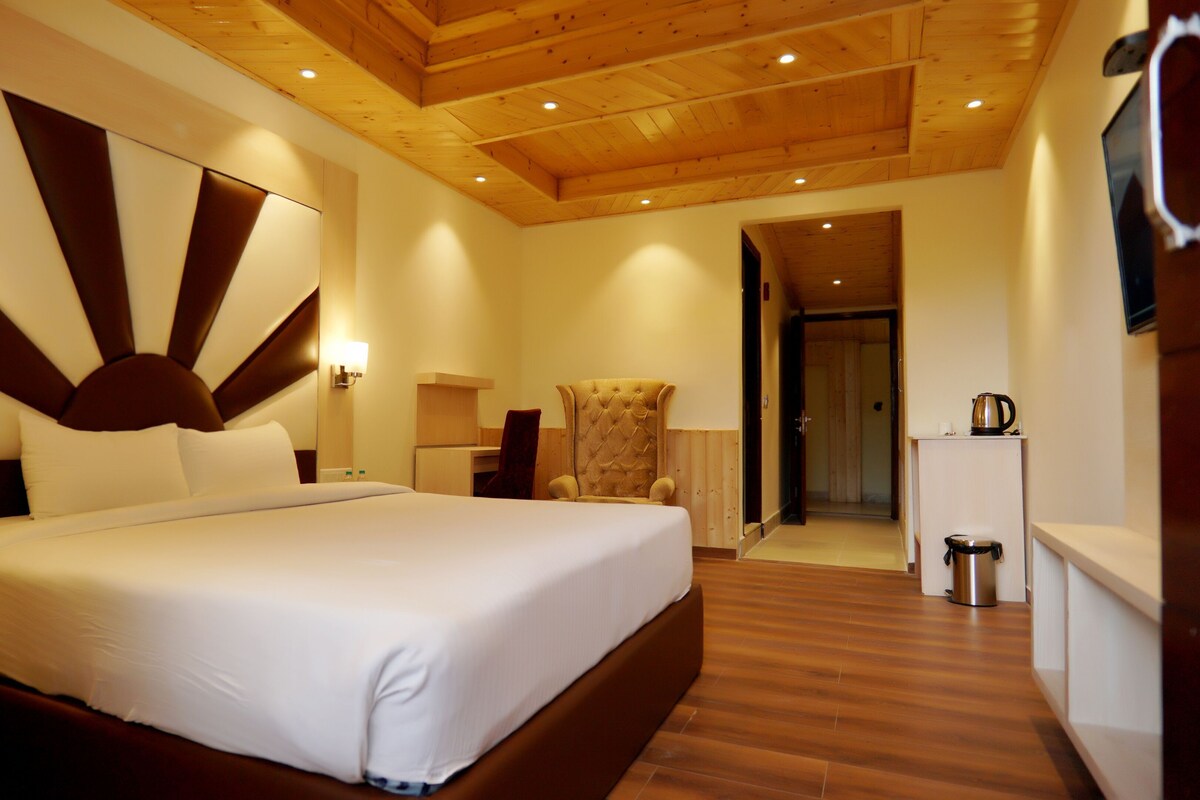 A hotel room with a large bed, a wooden ceiling, a desk, and a walk-in closet.