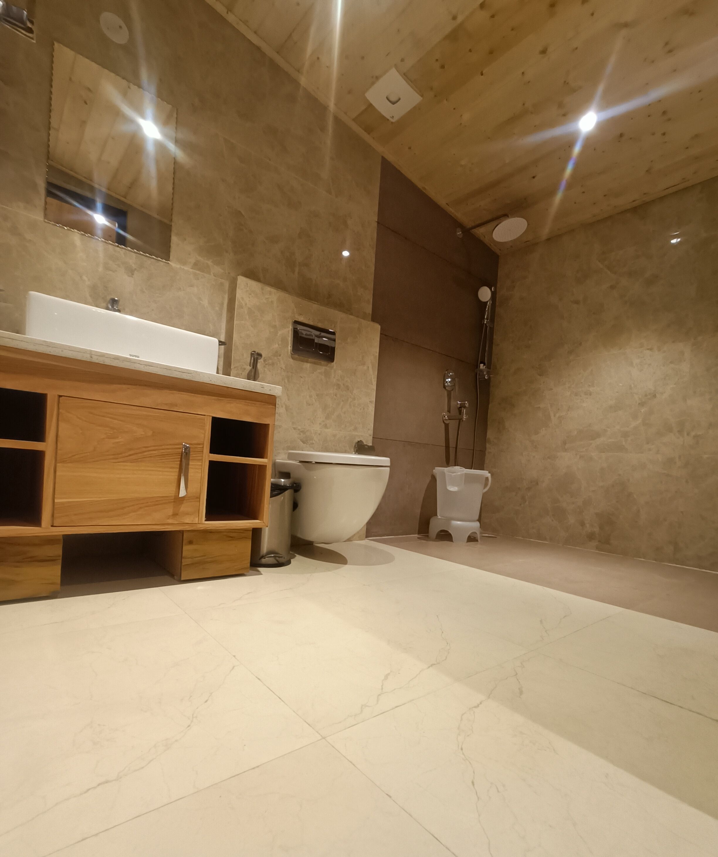Uma casa de banho moderna com toucador de madeira, lavatório branco e sanita.