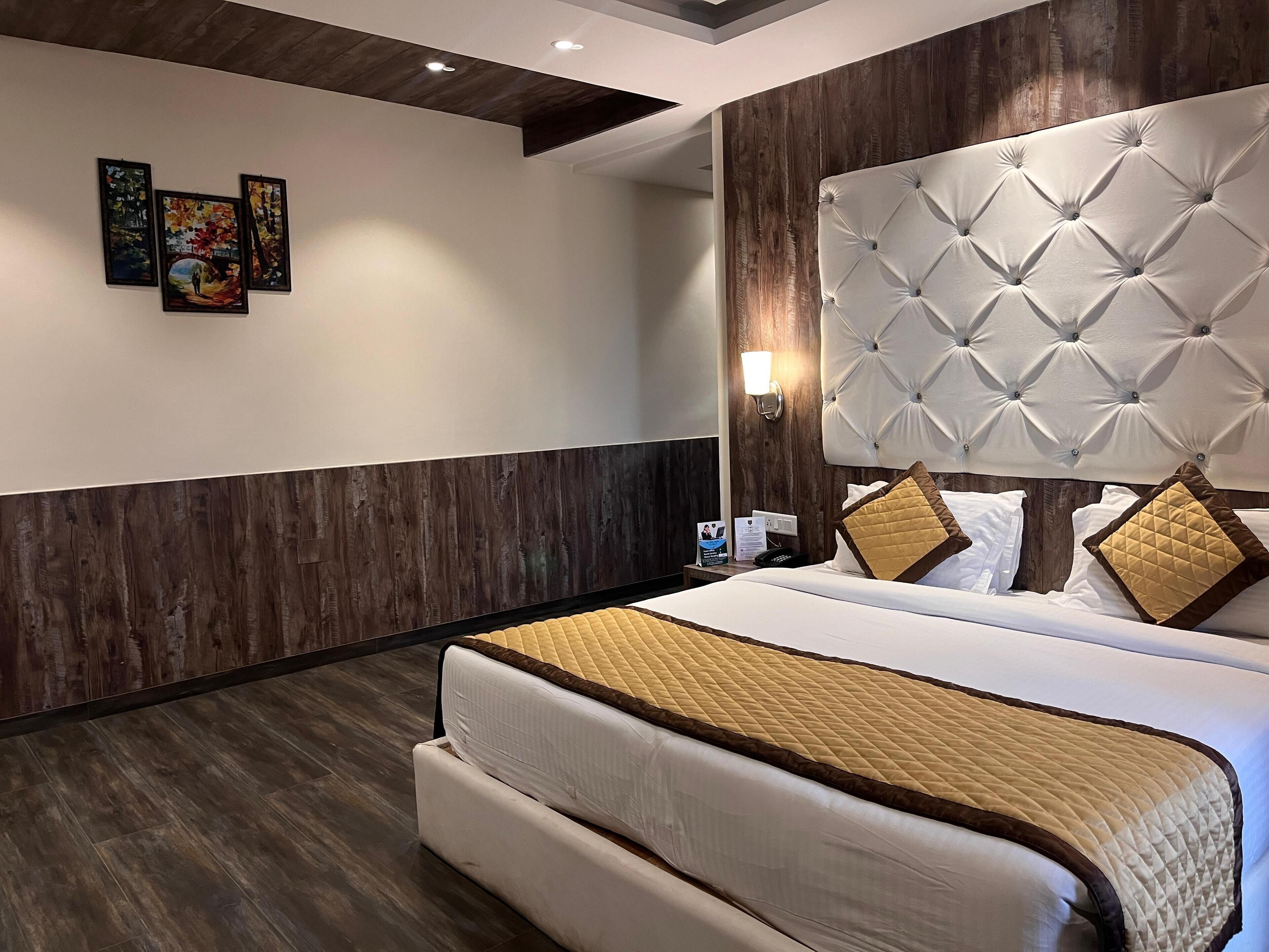 Une chambre d’hôtel moderne avec un grand lit, des murs lambrés et une tête de lit décorative.