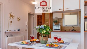 A dining area with a white table set for two, a vase of flowers, and two glasses of red wine. - Seafront apartment with terrace, wifi, pets allowed, spectacular views (Palamós)