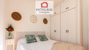 A bedroom with a bed, two pillows, a bedside table with a vase, and a wardrobe. - Seafront apartment with terrace, wifi, pets allowed, spectacular views (Palamós)