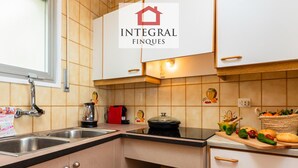 A modern kitchen with a sink, stove, and various kitchen appliances. There is a welcome sign and a basket of fruits on the counter. - Seafront apartment with terrace, wifi, pets allowed, spectacular views (Palamós)