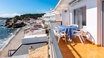 A balcony with a table and chairs overlooking a beach.