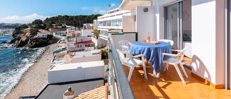 Un balcón con mesa y sillas con vista a la playa.