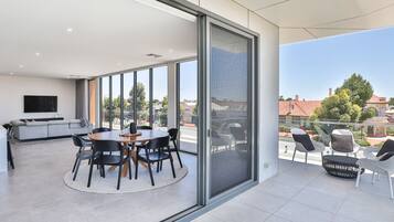Un espacio habitable moderno con comedor, sofá y balcón con mobiliario exterior.