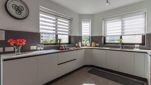 Una cucina moderna con mobili bianchi, un piano di lavoro nero e un orologio appeso al muro.