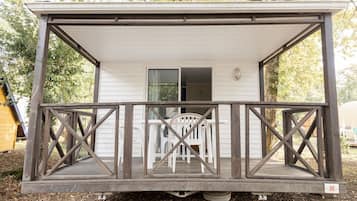 A small cabin with a wooden deck and a covered porch.