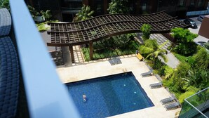 Ein Pool auf dem Dach mit einer gebogenen Holzpergola, umgeben von üppiger Bepflanzung und einigen Liegestühlen.