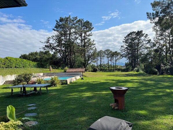 A backyard with a swimming pool, a barbecue grill, and a pergola.