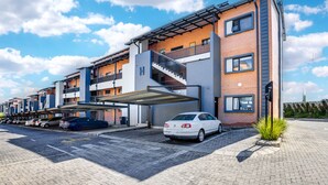 Un hotel moderno de varios pisos con una zona de estacionamiento techada y una escalera visible.