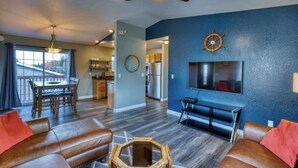 A modern living room with a large flat-screen TV, leather sofas, a ceiling fan, and a dining area with a view. - Adorable Alcove 2 Bedroom Escape Sleeps 4 (Kodiak)