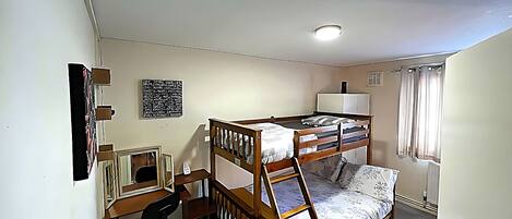 A bunk bed room with a desk, chair, and a lamp.