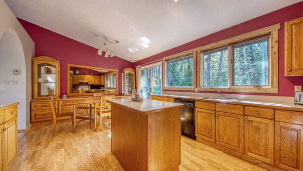 Una cocina amplia con armarios de madera, una isla central y ventanas grandes con vistas al exterior.
